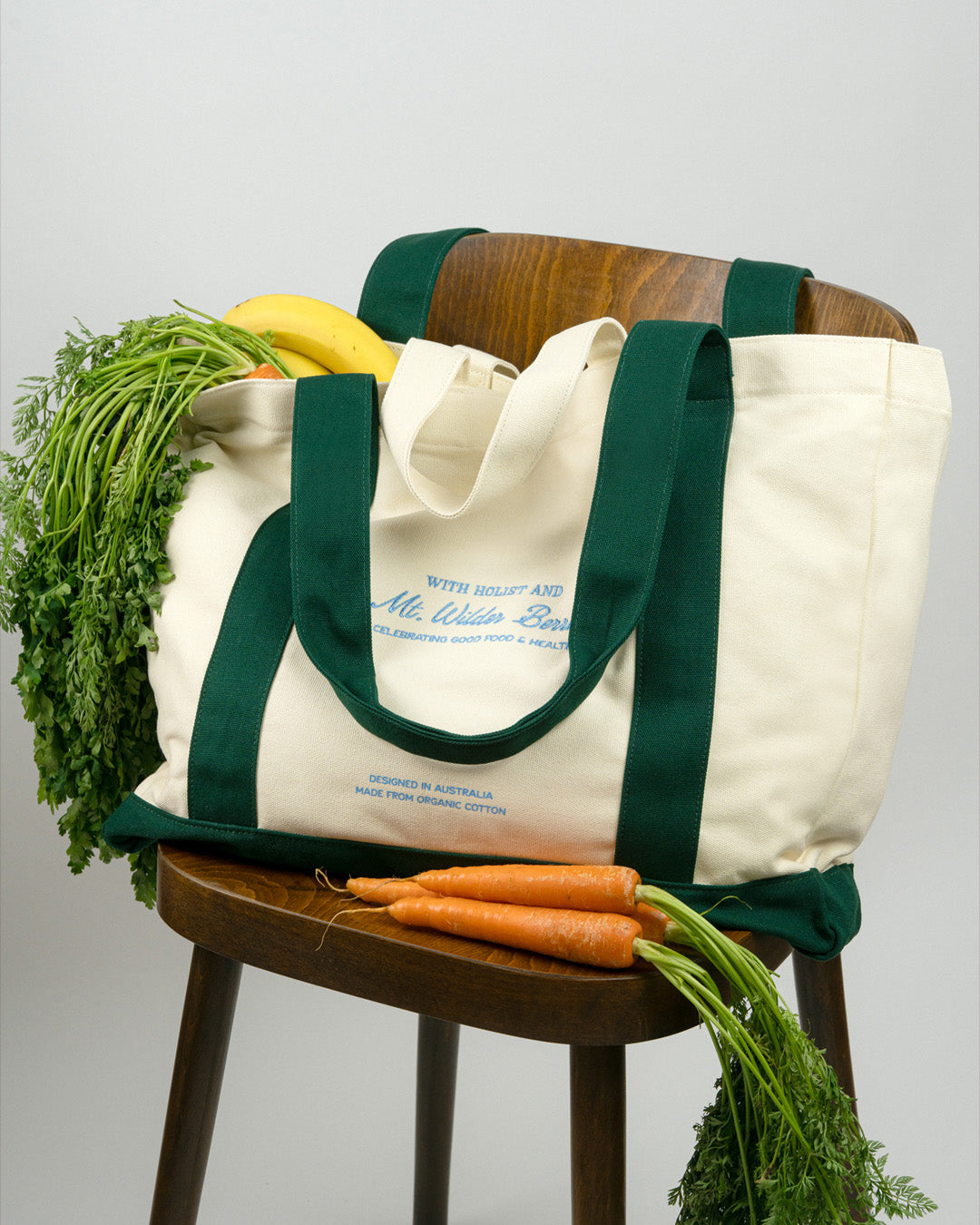 Tote bag with groceries on a wooden chair against a gray background