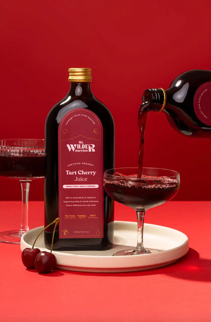 Wilder Tart Cherry Juice being poured into a glass with a red background