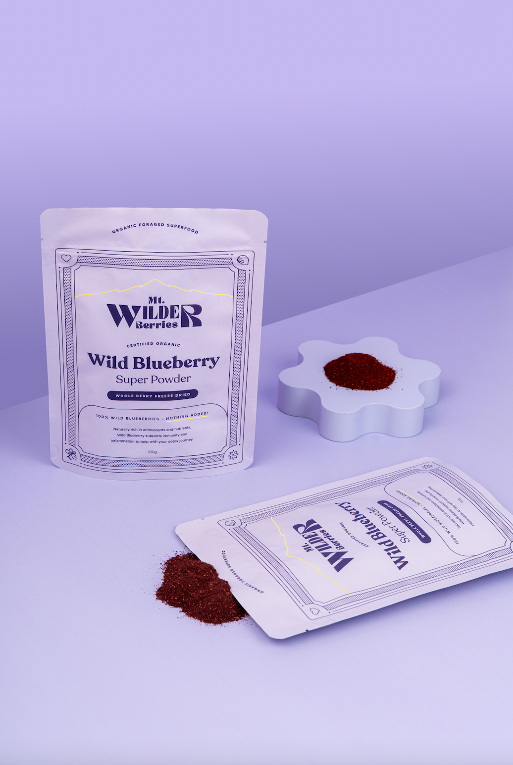 Two packages of Wild Blueberry Super Powder with a small amount of powder on a white surface.