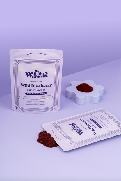 Two packages of Wild Blueberry Super Powder with a small amount of powder on a white surface.